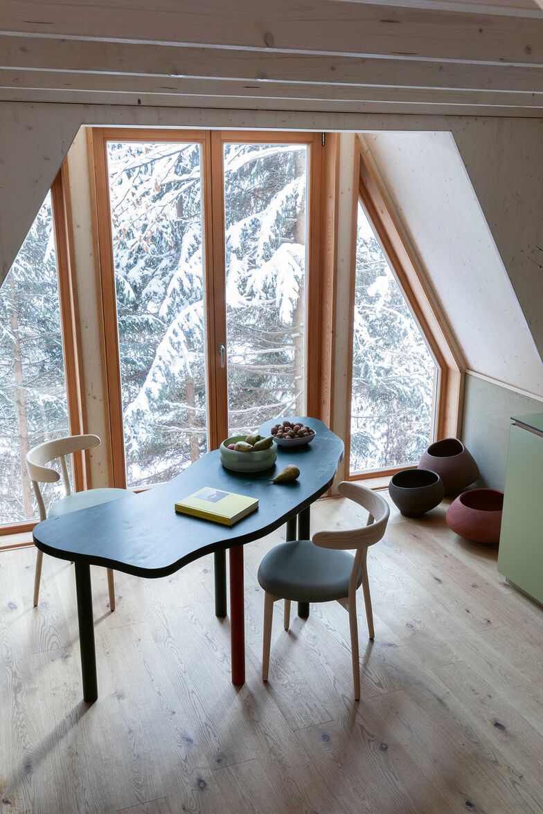 Das Fenster umrahmt den Wald, als sei er ein Gemälde, und der Esstisch spiegelt die Form des nahen Predilsees wider.