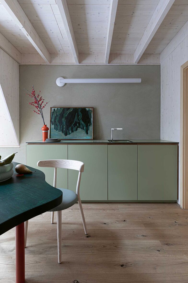 Die Einrichtung ist virtuos auf die Landschaft abgestimmt. So erinnern das Moosgrün der Designerküche und die beerenrote Vase an den Waldboden vor der Türe.