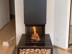 Eigenkreation: Der eckige Warmluftofen «Utaro» kann individuell mit einem in Steffisburg gefertigten Feuermöbel mit Holzfach oder Schublade ergänzt werden. Baumann.