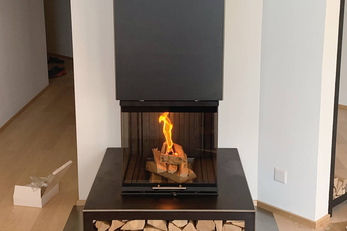Eigenkreation: Der eckige Warmluftofen «Utaro» kann individuell mit einem in Steffisburg gefertigten Feuermöbel mit Holzfach oder Schublade ergänzt werden. Baumann.