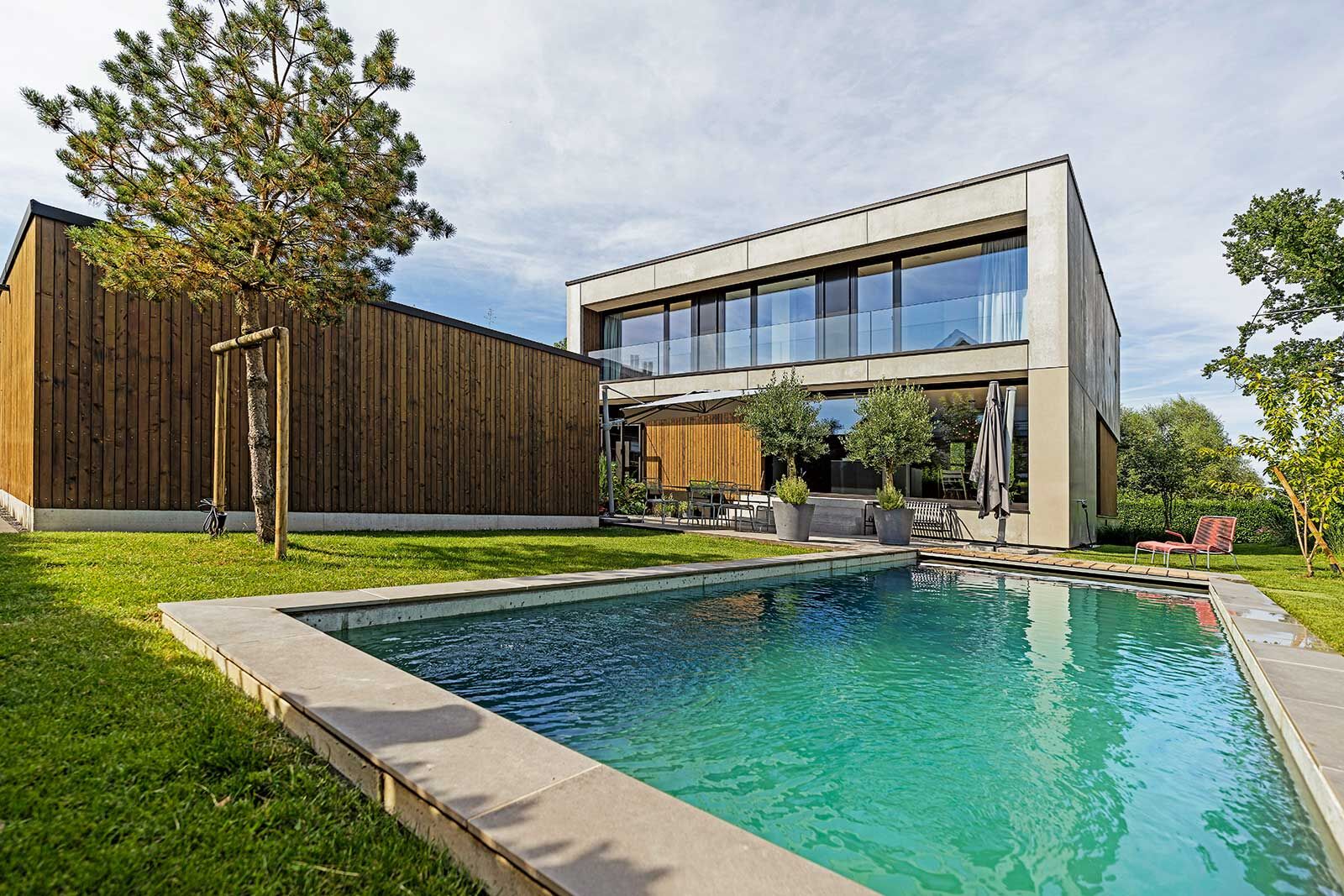Der kubische Baukörper mit seiner Betonelementfassade und Holzverkleidung ruht auf einem Hochparterre. Der Bodensee auf der Nordseite ist nicht nur in Sichtweite, er ist nicht mehr als einen Schilfstreifen vom Grundstück entfernt.