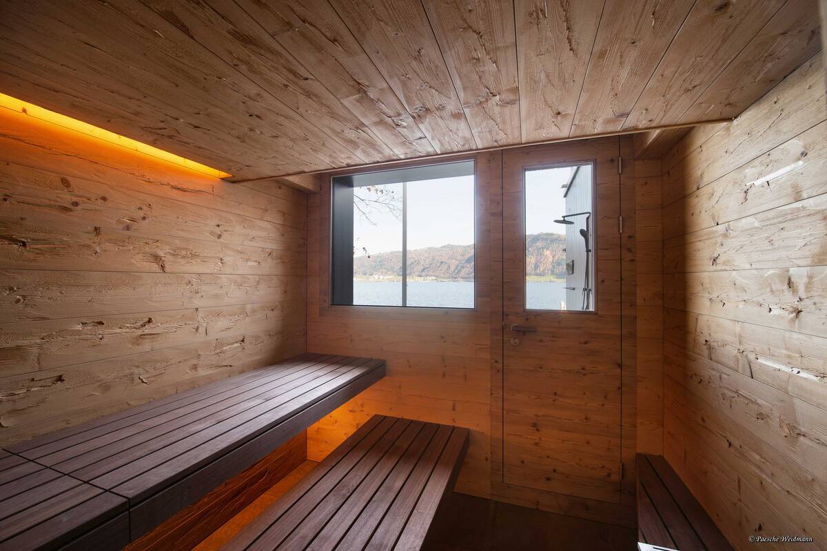 Die extralange Liegefläche direkt vor dem Fenster mit Blick auf den See war ein Wunsch der Bauherrschaft. Ebenso die Tür, die direkten Zugang zum Aussenplatz und zum Sprung ins kühle Nass bietet. Küng Wellness AG.