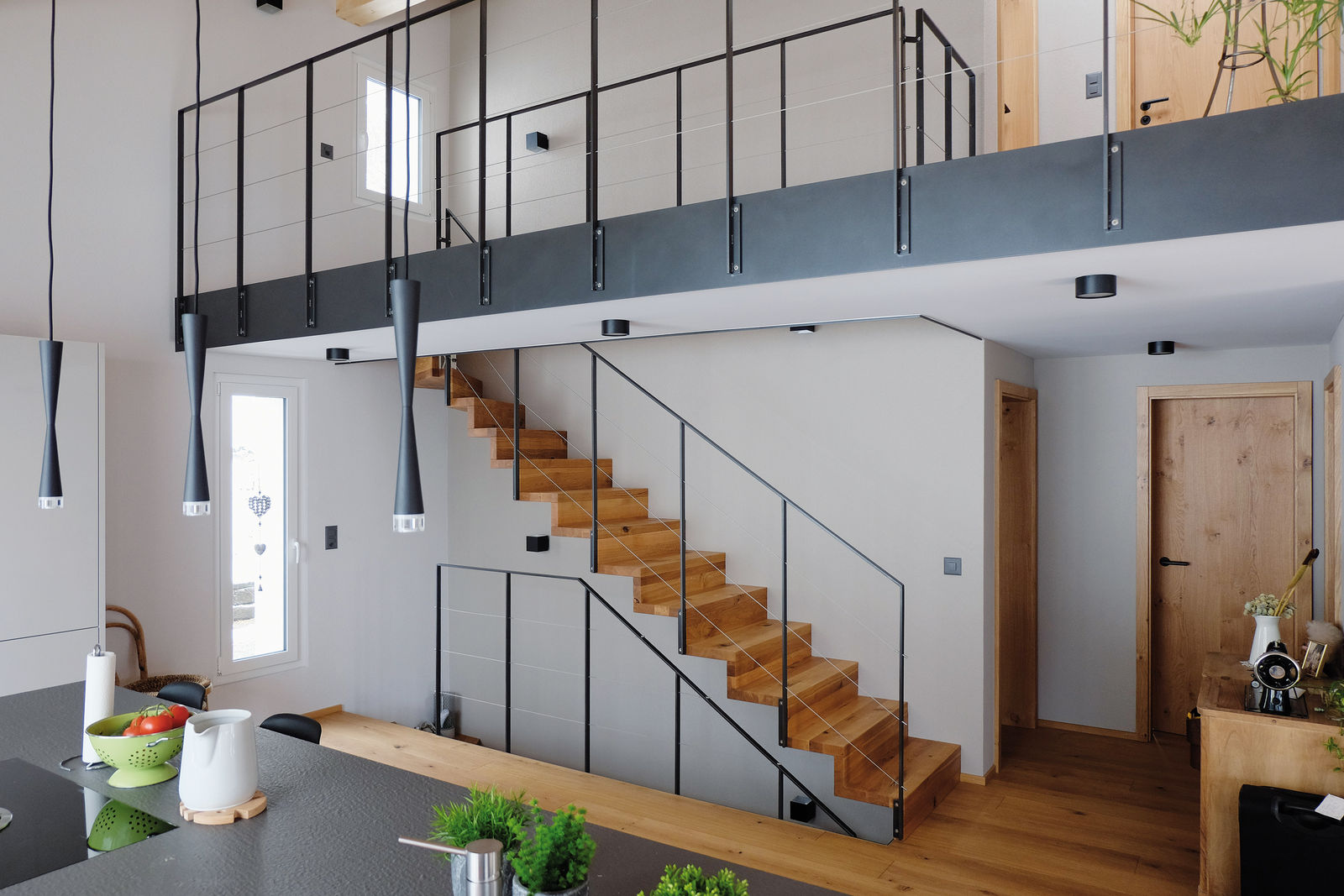 Passt zum Parkett: 1/4 gewendelte Faltwerktreppe mit massiven Eichenstufen. Holz: Eiche Country mit schwarz gespachtelten Ästen und Rissen, gebürstet und geölt. Geländer: pulverbeschichtete Flachstahlbrüstungen mit gespannten Chrom-Nickel-Stahlseilen. Columbus Treppen AG.