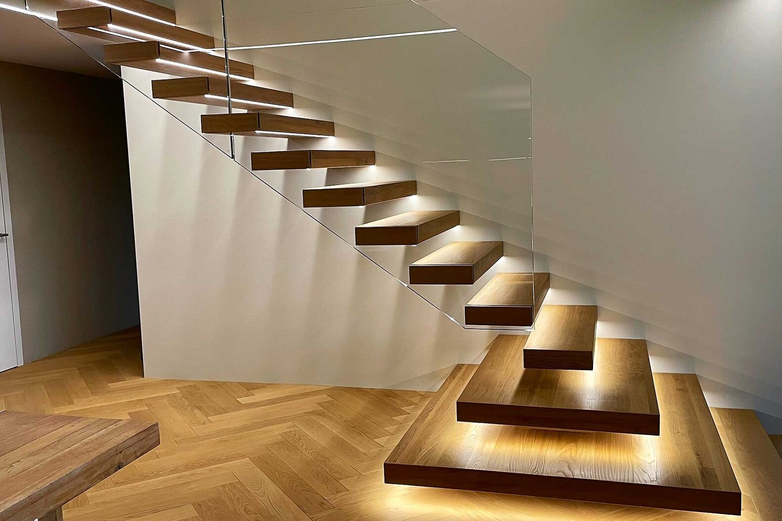 Die beiden untersten Stufen bilden ein Antrittspodest für einen schöneren Einstieg. Unter den Stufen ist eine LED-Beleuchtung eingefräst. Langegg Treppenbau, www.langegg.ch